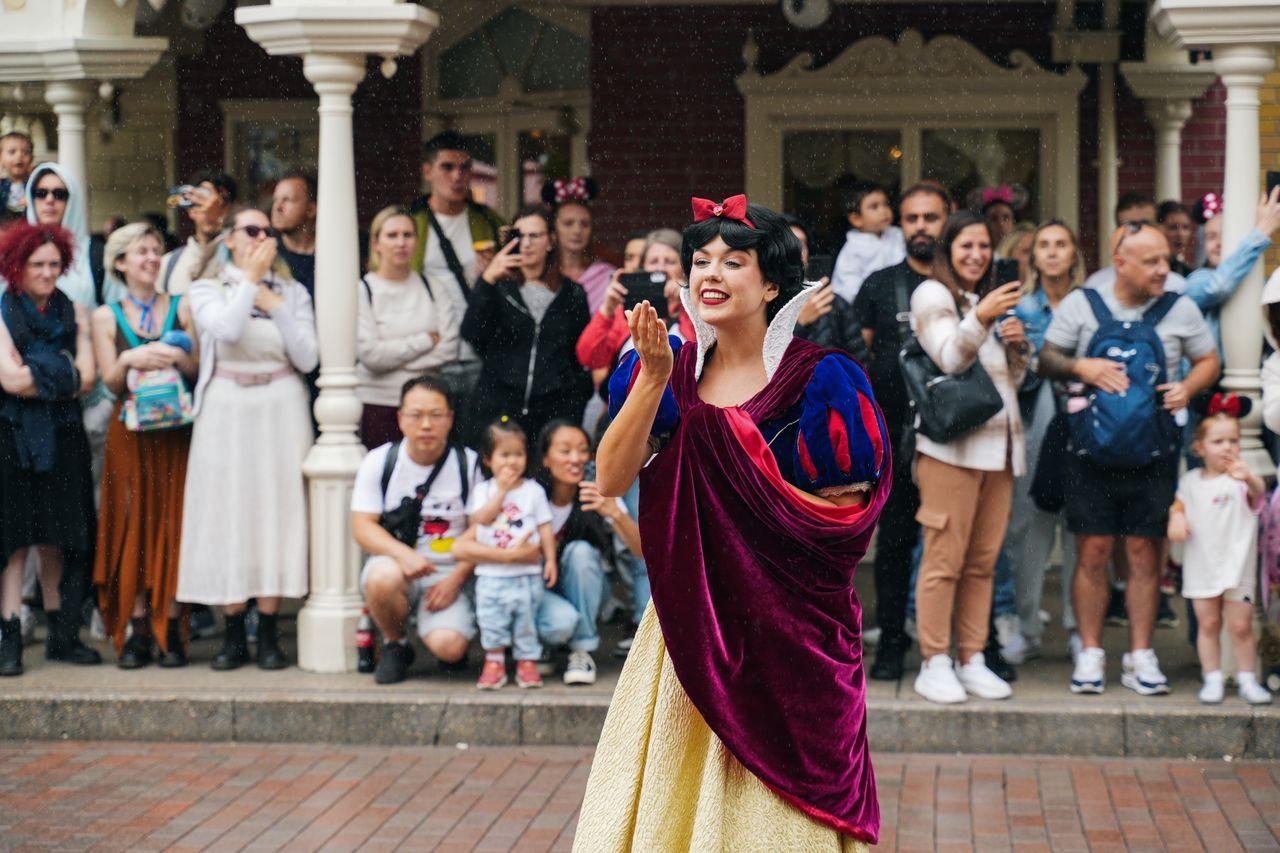 Snow White entertains a crowd at Disneyland Paris with joyful gestures.